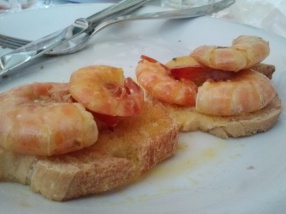 Scampi con arancia su crostini, shrimp cooked in an orange sauce on toast